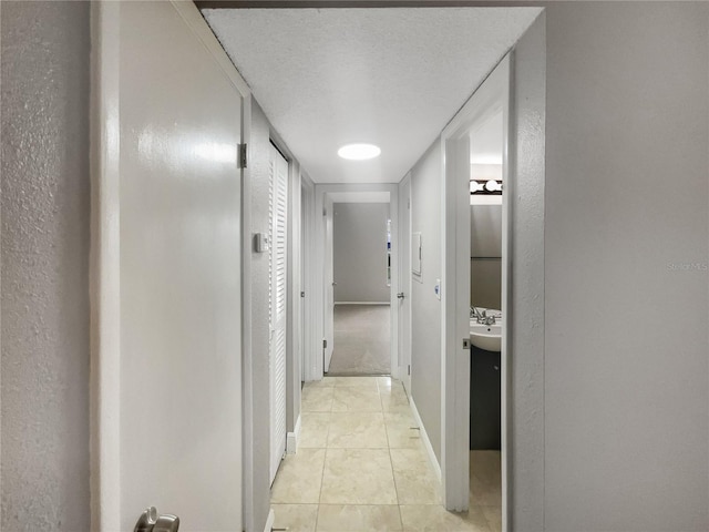 corridor featuring a textured ceiling and light tile patterned floors