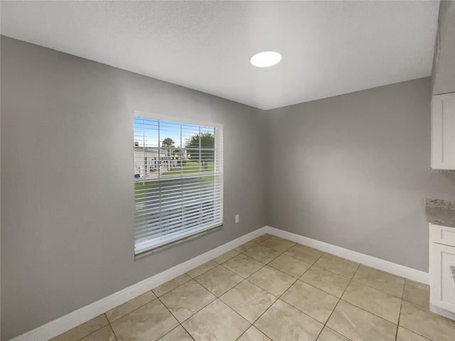 unfurnished dining area featuring light tile patterned floors and a textured ceiling