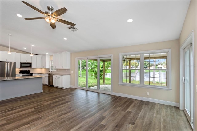 kitchen with dark wood-type flooring, vaulted ceiling, hanging light fixtures, stainless steel appliances, and white cabinets