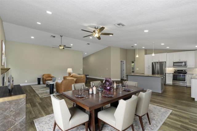 dining space featuring ceiling fan, dark wood-type flooring, vaulted ceiling, and a textured ceiling