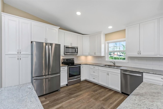 kitchen featuring stainless steel appliances, white cabinetry, light stone countertops, and sink