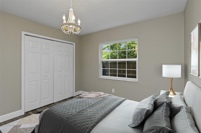 bedroom with a notable chandelier, dark wood-type flooring, a closet, and a textured ceiling