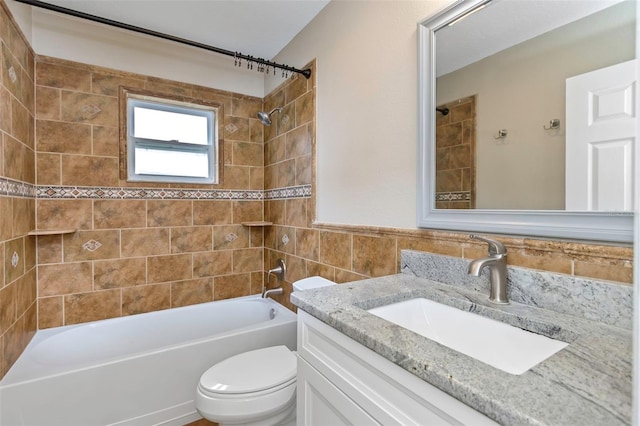 full bathroom with tiled shower / bath, tile walls, vanity, and toilet