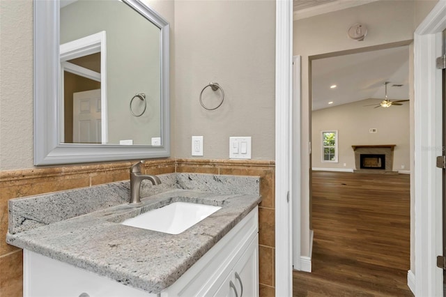 bathroom featuring lofted ceiling, tile walls, vanity, ceiling fan, and hardwood / wood-style floors