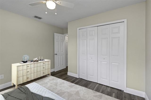 unfurnished bedroom with ceiling fan, dark hardwood / wood-style flooring, a closet, and a textured ceiling