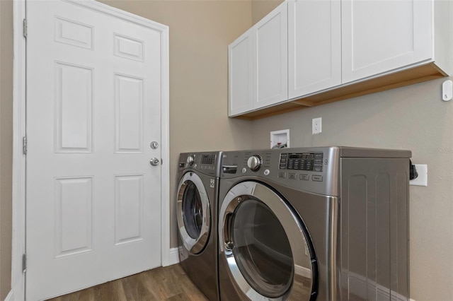 washroom featuring cabinets, dark hardwood / wood-style flooring, and washing machine and clothes dryer