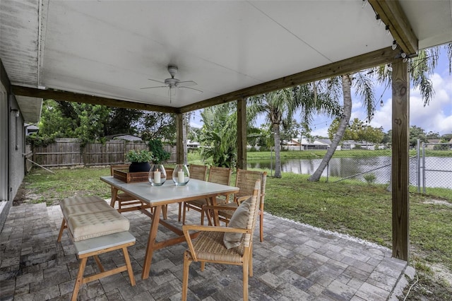 view of patio with a water view and ceiling fan