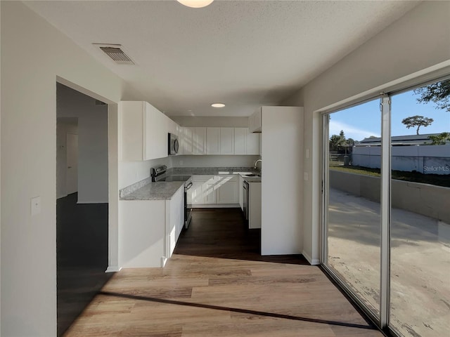 kitchen with sink, white cabinets, stainless steel appliances, dark wood-type flooring, and a textured ceiling