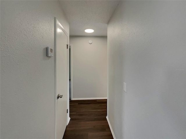 hall with dark hardwood / wood-style flooring and a textured ceiling