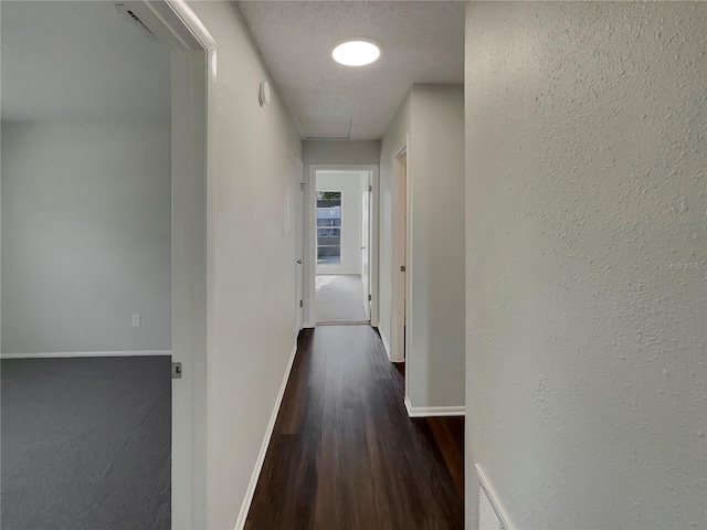 corridor with dark hardwood / wood-style floors and a textured ceiling