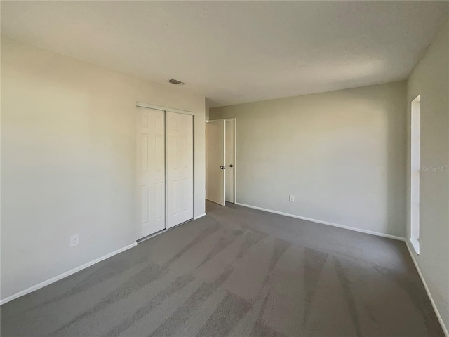 unfurnished bedroom featuring dark carpet and a closet