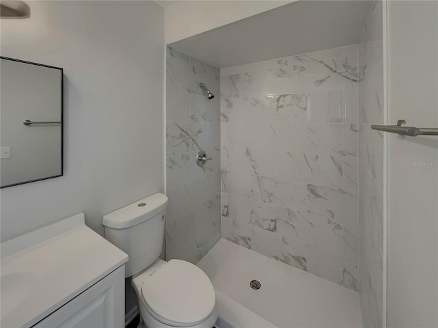 bathroom featuring vanity, toilet, and a tile shower