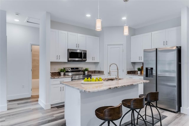 kitchen featuring sink, stainless steel appliances, an island with sink, and white cabinets