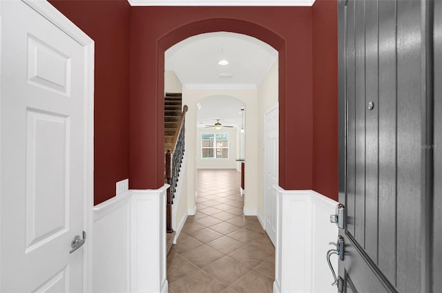 hall featuring light tile patterned floors and crown molding