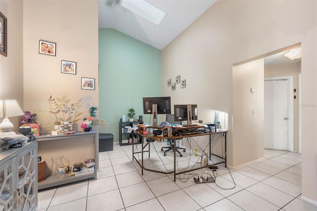 office space featuring light tile patterned floors, a skylight, and high vaulted ceiling