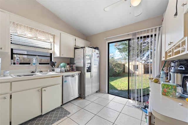 kitchen featuring lofted ceiling, sink, light tile patterned floors, stainless steel appliances, and white cabinets