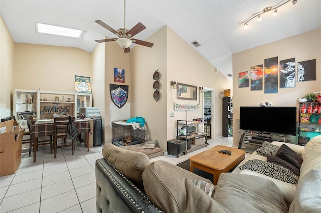 living room with light tile patterned flooring, high vaulted ceiling, ceiling fan, and a skylight