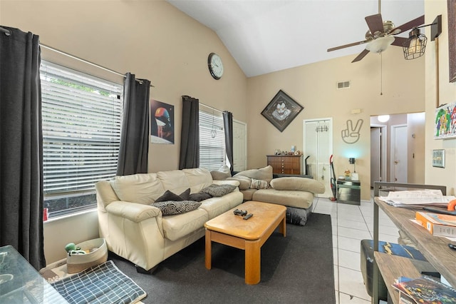 tiled living room with ceiling fan and high vaulted ceiling