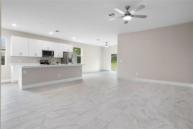 kitchen featuring a kitchen island with sink, white cabinetry, stainless steel appliances, and ceiling fan