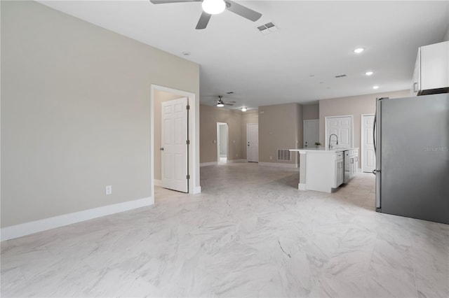 kitchen featuring white cabinetry, a center island with sink, ceiling fan, and stainless steel refrigerator