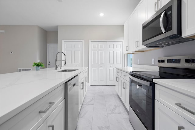 kitchen featuring white cabinetry, sink, stainless steel appliances, and light stone countertops