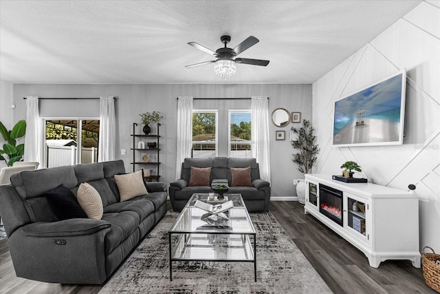 living room with ceiling fan, plenty of natural light, dark hardwood / wood-style flooring, and a textured ceiling