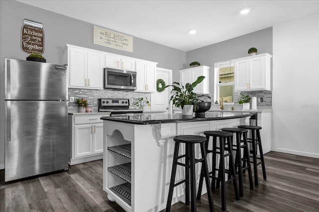 kitchen with a breakfast bar, dark hardwood / wood-style floors, white cabinetry, a center island, and stainless steel appliances