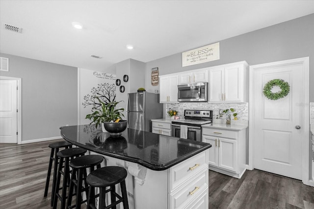 kitchen featuring a kitchen island, a breakfast bar, tasteful backsplash, white cabinetry, and stainless steel appliances