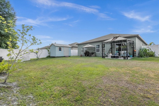 rear view of property featuring a gazebo, a lawn, glass enclosure, and a storage unit