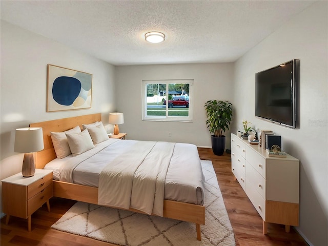 bedroom featuring light hardwood / wood-style floors and a textured ceiling