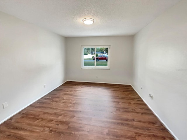 spare room with dark hardwood / wood-style floors and a textured ceiling