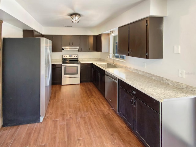 kitchen with appliances with stainless steel finishes, sink, dark brown cabinets, and light hardwood / wood-style floors