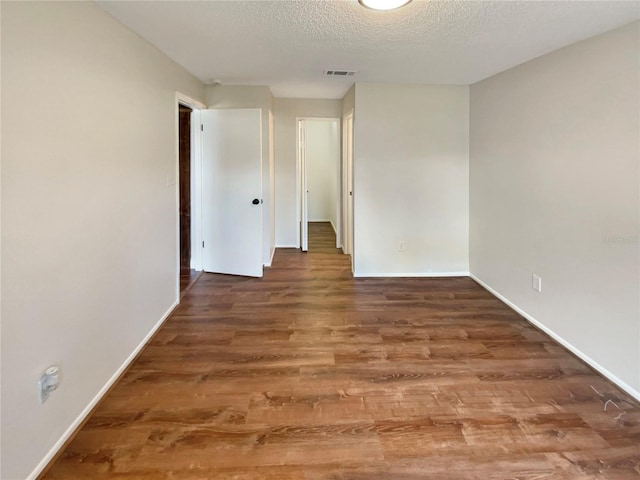 unfurnished room featuring dark hardwood / wood-style floors and a textured ceiling