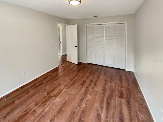 unfurnished bedroom featuring dark hardwood / wood-style flooring, a closet, and a textured ceiling