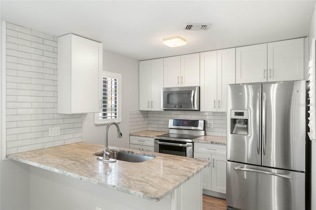 kitchen featuring white cabinetry, stainless steel appliances, kitchen peninsula, and sink