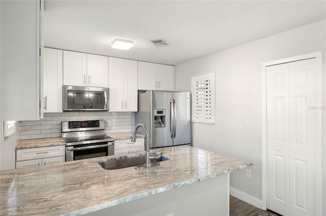 kitchen with white cabinetry, light stone countertops, stainless steel appliances, and sink