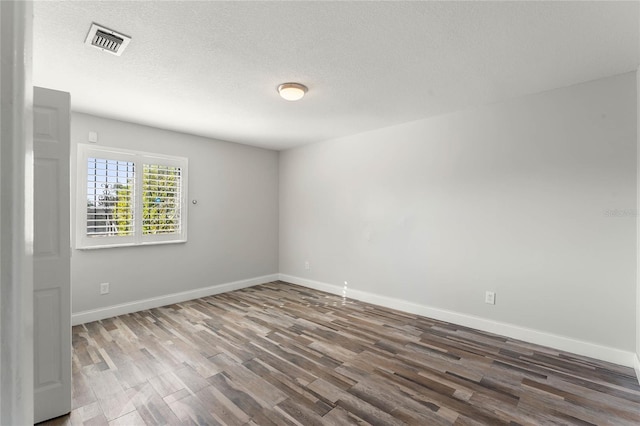 spare room with dark wood-type flooring and a textured ceiling