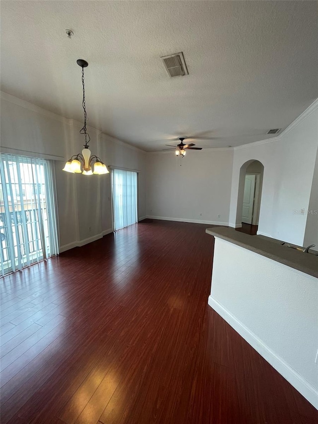 spare room featuring ceiling fan with notable chandelier, ornamental molding, dark hardwood / wood-style floors, and a textured ceiling