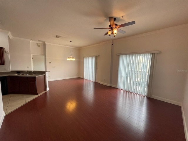 unfurnished living room featuring ceiling fan with notable chandelier, sink, crown molding, and hardwood / wood-style floors