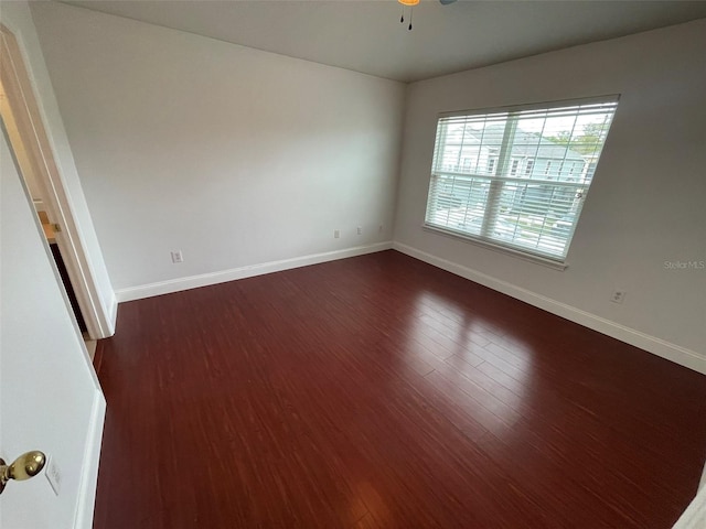 empty room with dark wood-type flooring and ceiling fan