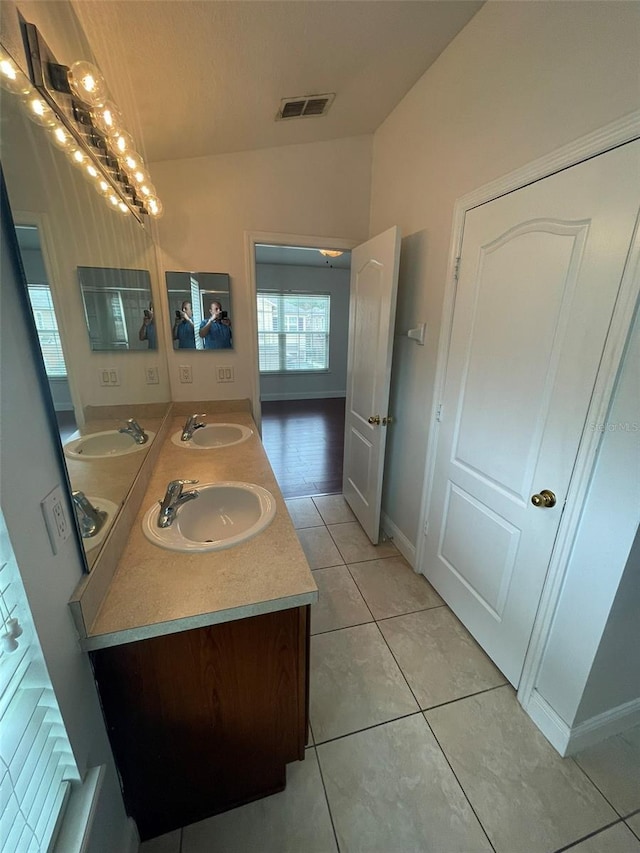 bathroom featuring tile patterned flooring, vanity, and vaulted ceiling