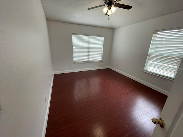 empty room with dark wood-type flooring, a wealth of natural light, and ceiling fan