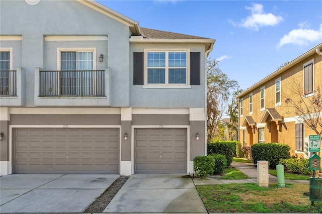 multi unit property featuring a garage, roof with shingles, driveway, and stucco siding