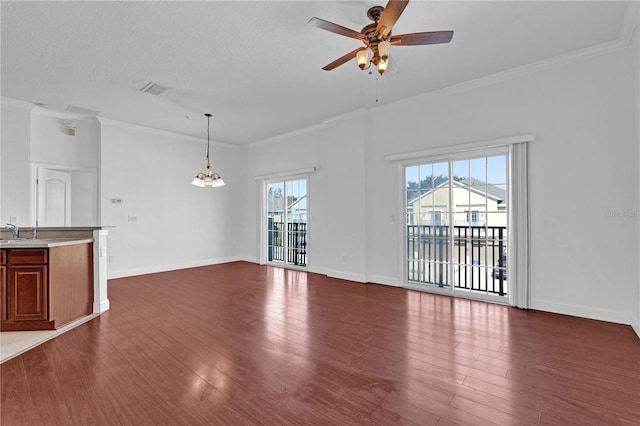 unfurnished living room featuring ceiling fan with notable chandelier, dark wood-type flooring, a sink, baseboards, and ornamental molding