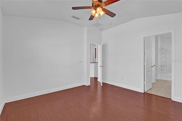 unfurnished bedroom with lofted ceiling, visible vents, light wood-style flooring, and baseboards