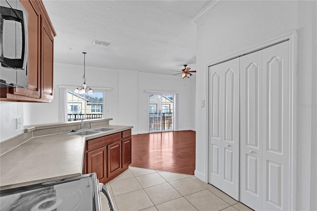 kitchen featuring visible vents, stove, light countertops, a sink, and light tile patterned flooring