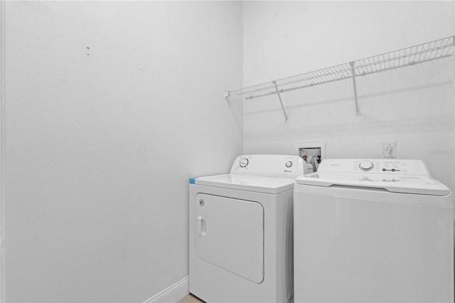 clothes washing area with laundry area, washing machine and clothes dryer, and baseboards