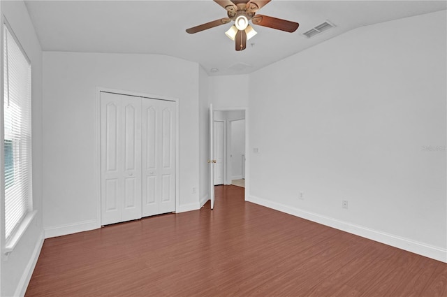 unfurnished bedroom featuring lofted ceiling, dark wood-style flooring, multiple windows, and visible vents