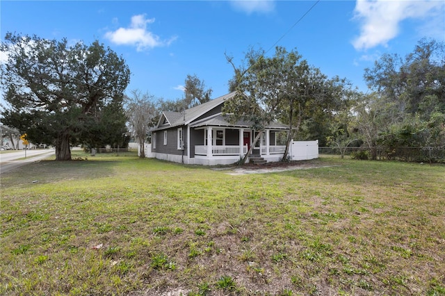 view of side of property featuring covered porch and a lawn