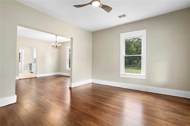 spare room featuring dark wood-type flooring and ceiling fan with notable chandelier